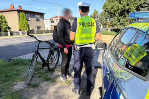 Na zdjęciu widać policjanta i mężczyznę przy radiowozie i rowerze.