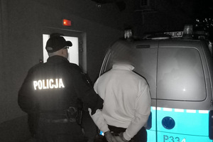 Na zdjęciu widać zatrzymanego mężczyznę oraz policjanta i radiowóz.