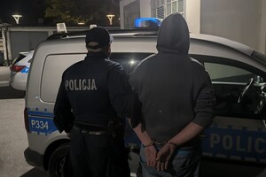 Na zdjęciu widać policjanta, zatrzymanego mężczyznę oraz radiowóz.