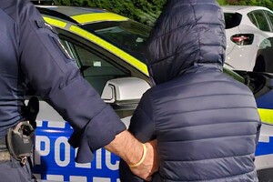 Na zdjęciu widać radiowóz, kobietę w ciemnej kurtce oraz policjanta.