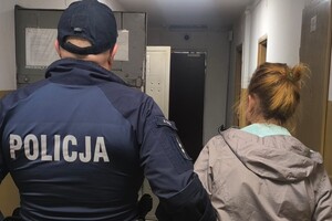 Na zdjęciu widać korytarz, policjanta i kobietę.