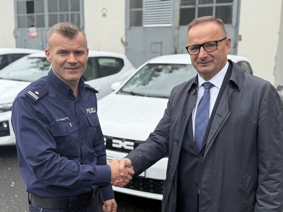 Na zdjęciu widać policjanta oraz Prezydenta Miasta a w tle biały samochód.