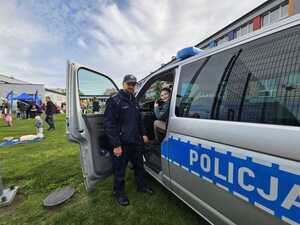 Na zdjęciu widać policjanta, radiowóz oraz festyn przed szkołą.