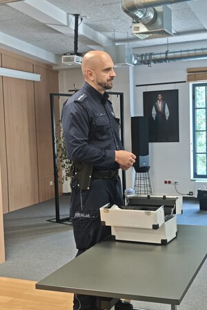 Na zdjęciu widać policjanta oraz uczestników spotkania.