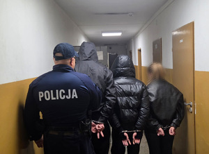 Na zdjęciu widać policjanta oraz zatrzymane osoby.