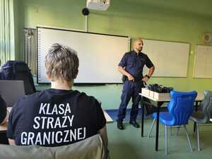 Na zdjęciu widać policjanta oraz uczniów.