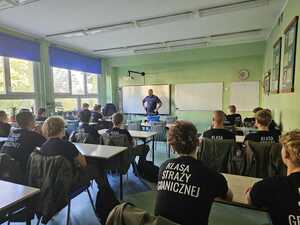 Na zdjęciu widać policjanta oraz uczniów.