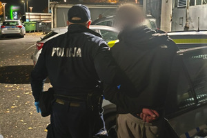 Na zdjęciu widać zatrzymanego mężczyznę, radiowóz oraz policjanta.